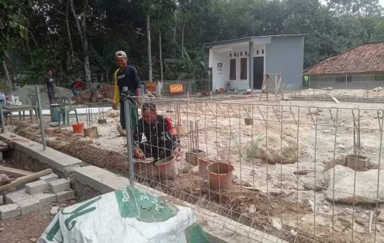 Anggota Babinsa Koramil Purwadadi bersama warga Desa Wanakerta sedang bahu-membahu melakukan pengecoran pondasi rumah di Subang.