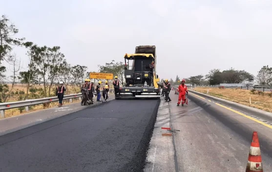 Pekerja dan petugas pengatur lalu lintas saat menangani proyek perbaikan jalan tol di ruas Cikopo-Palimanan dengan rambu-rambu pengaman.