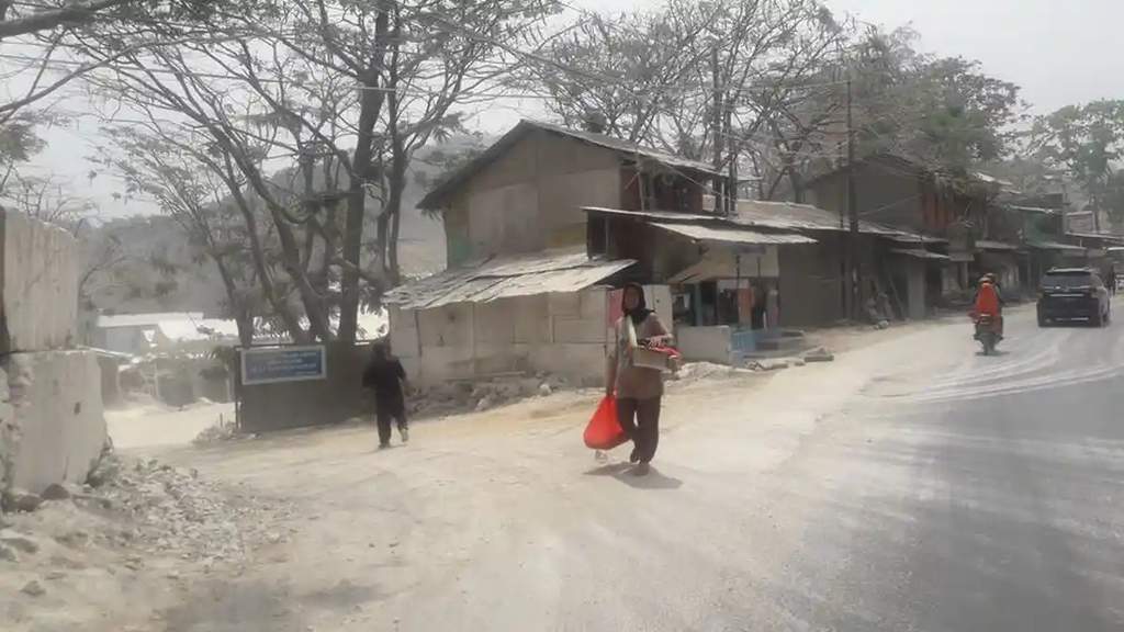 Kondisi lingkungan berdebu di kawasan penambangan batu kapur dengan aktivitas warga yang melintas menggunakan masker pelindung di Padalarang, Bandung Barat.